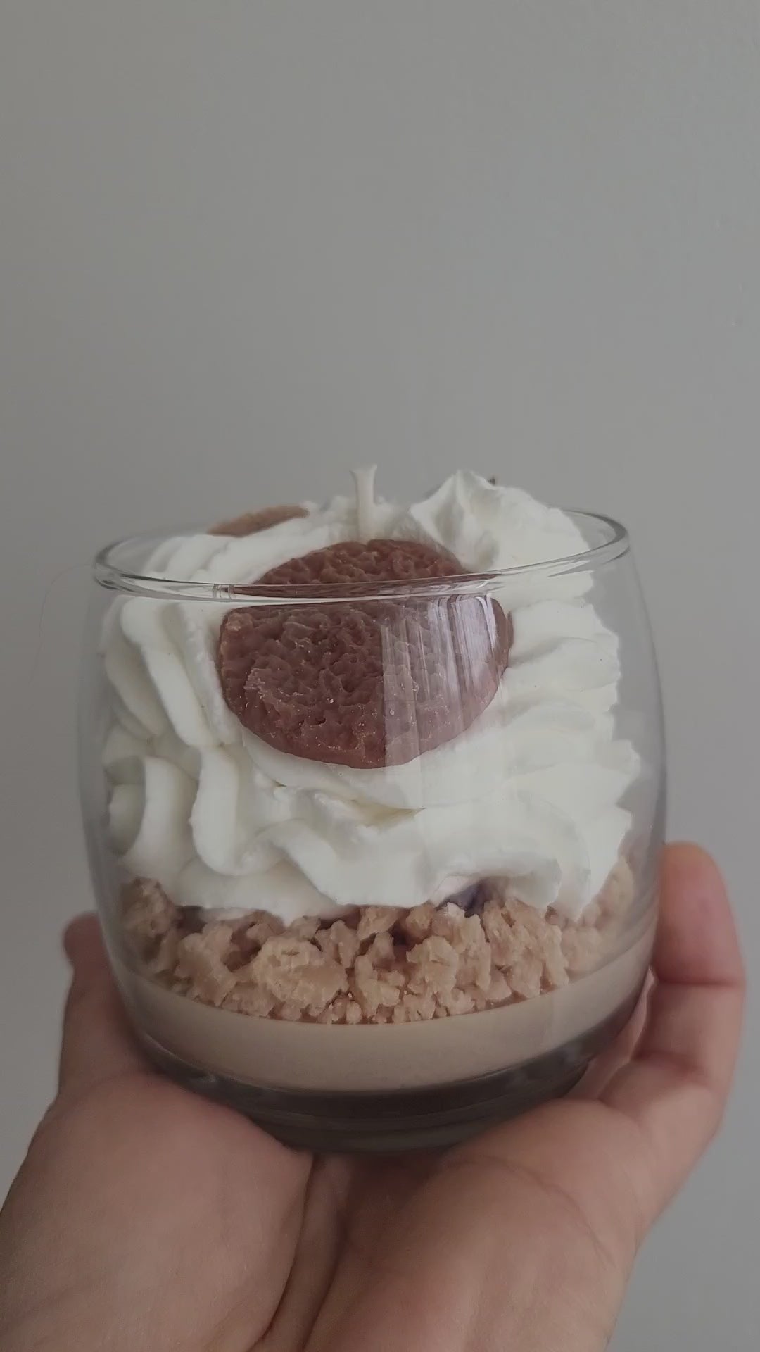  Gros plan vidéo d’une bougie artisanale parfum Éclats de Cookies, chantilly blanche avec crumble marron et petits cookies décoratifs, dévoilant les détails gourmands et la finition artisanale.
