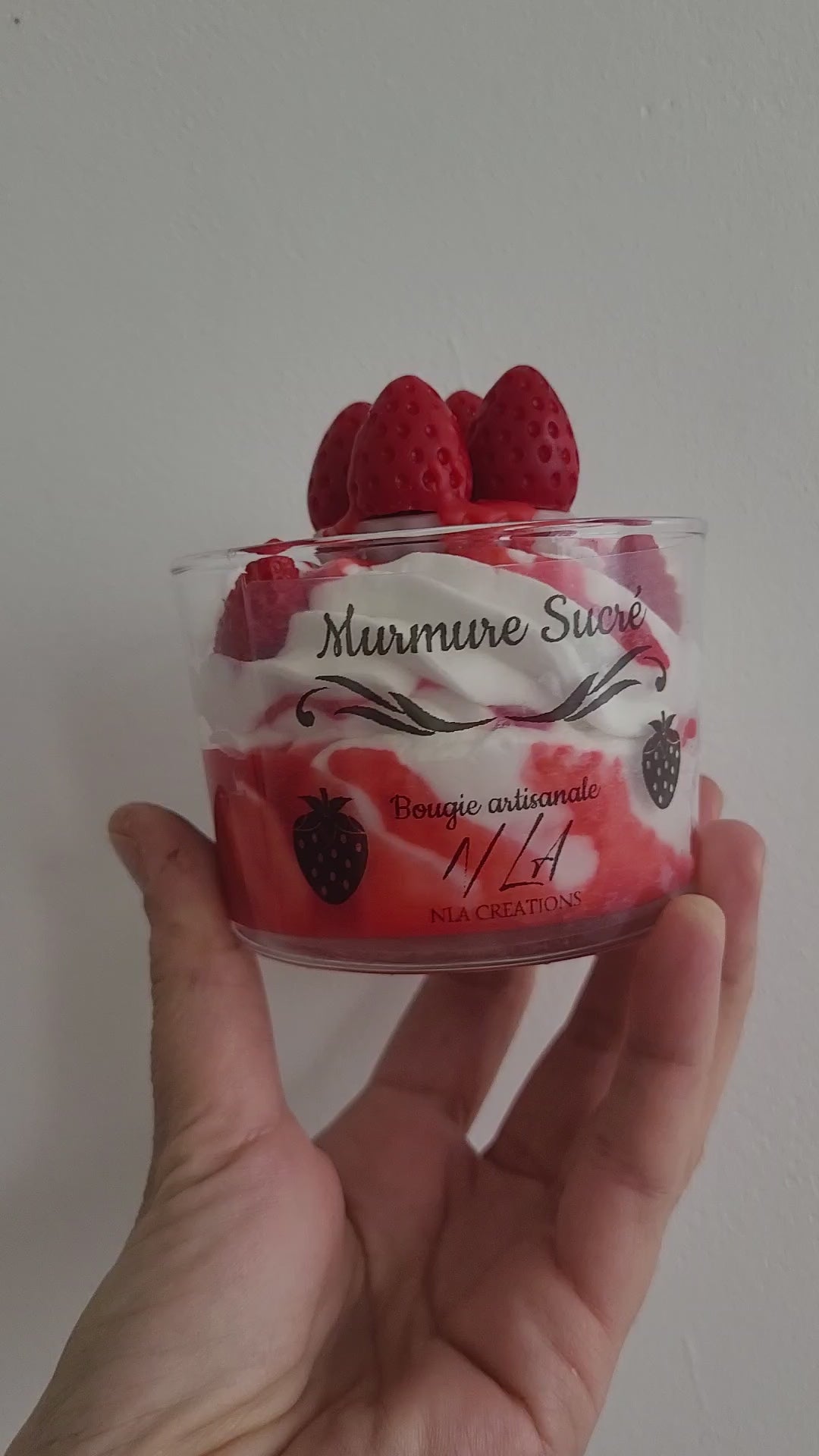 Gros plan vidéo d’une bougie artisanale parfum Murmure Sucré Fraise, chantilly blanche avec coulis rouge et petite tarte aux quatre fraises, montrant les détails gourmands et faits main.
