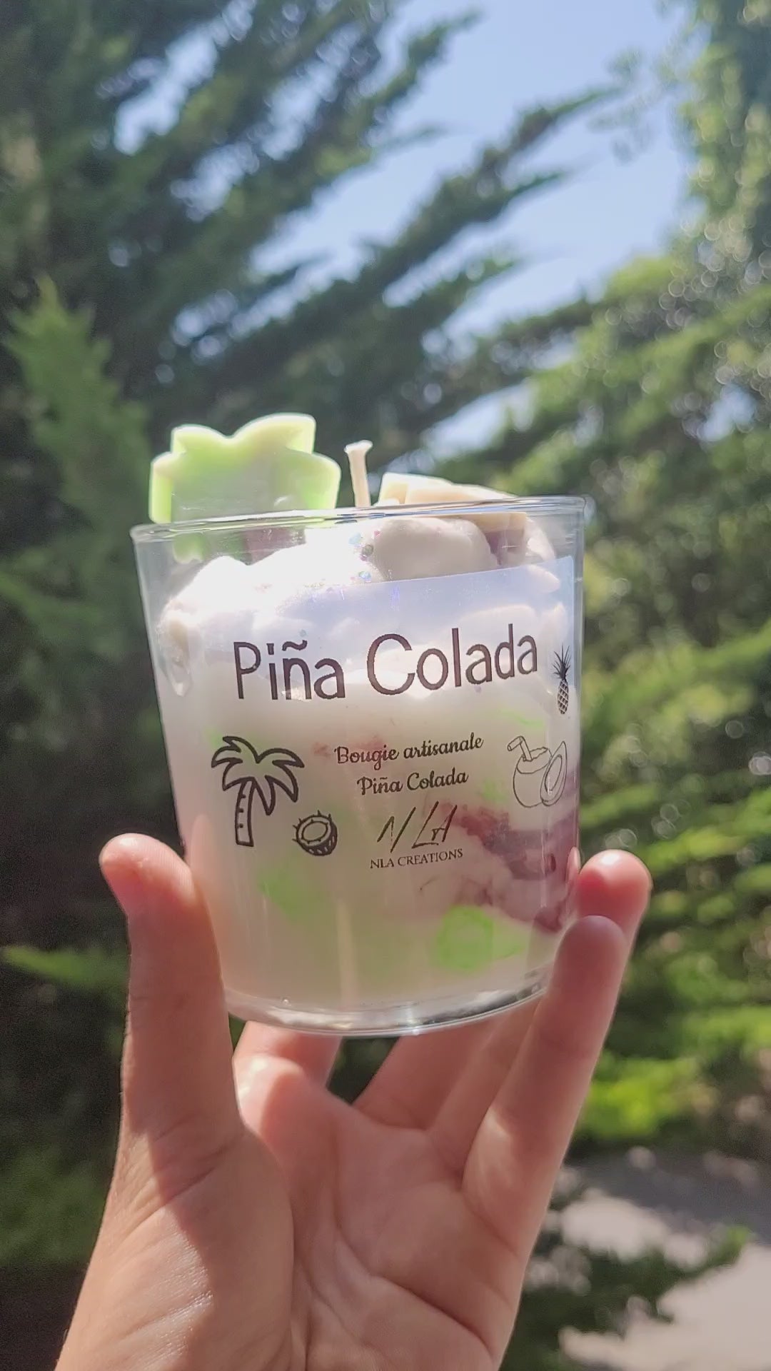 Bougie artisanale Pina Colada avec décoration en cire en forme de palmier, photographiée en extérieur sous le soleil