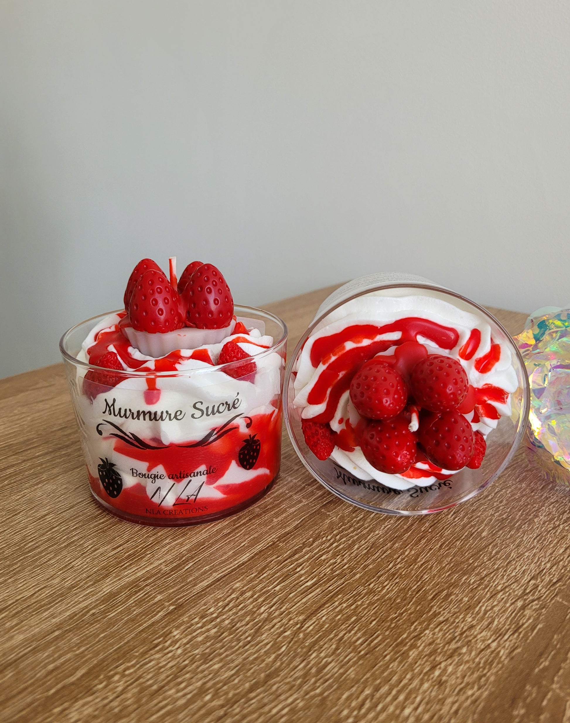 Vue du dessus d’une bougie artisanale parfum Murmure Sucré Fraise, chantilly blanche avec coulis rouge, mettant en avant la petite tarte garnie de quatre fraises fraîches, détails faits main.
