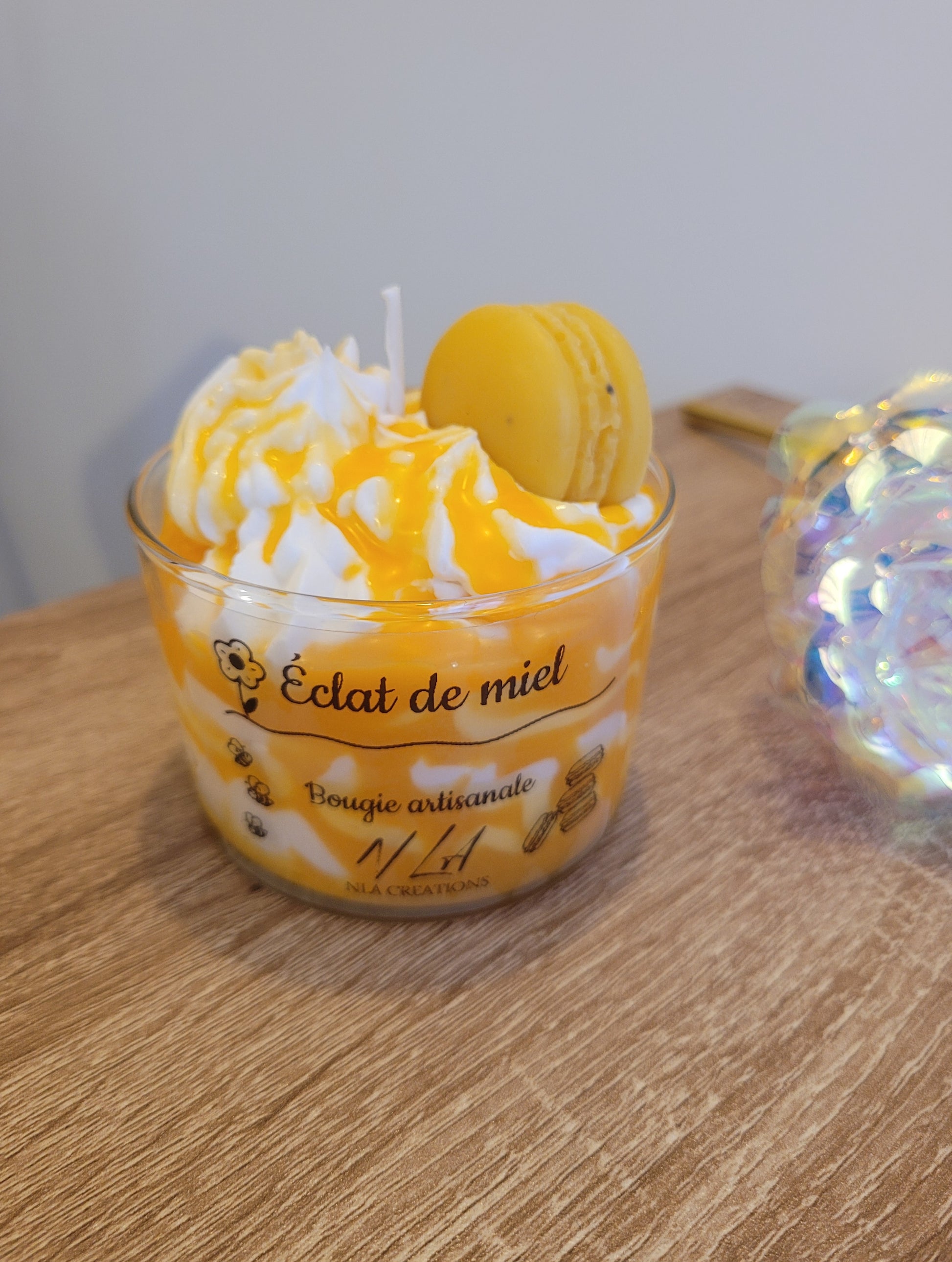 Gros plan sur une bougie artisanale parfum Miel Avoine, avec une surface crémeuse couleur miel clair, décorée de touches d’avoine naturelle, mettant en valeur sa texture douce et artisanale.