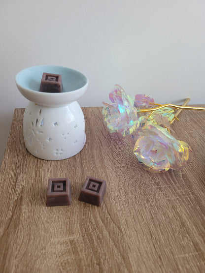 Petit fondant artisanal en forme de carré, couleur chocolat, évoquant la chaleur et la gourmandise d’une tasse de chocolat chaud fumant.