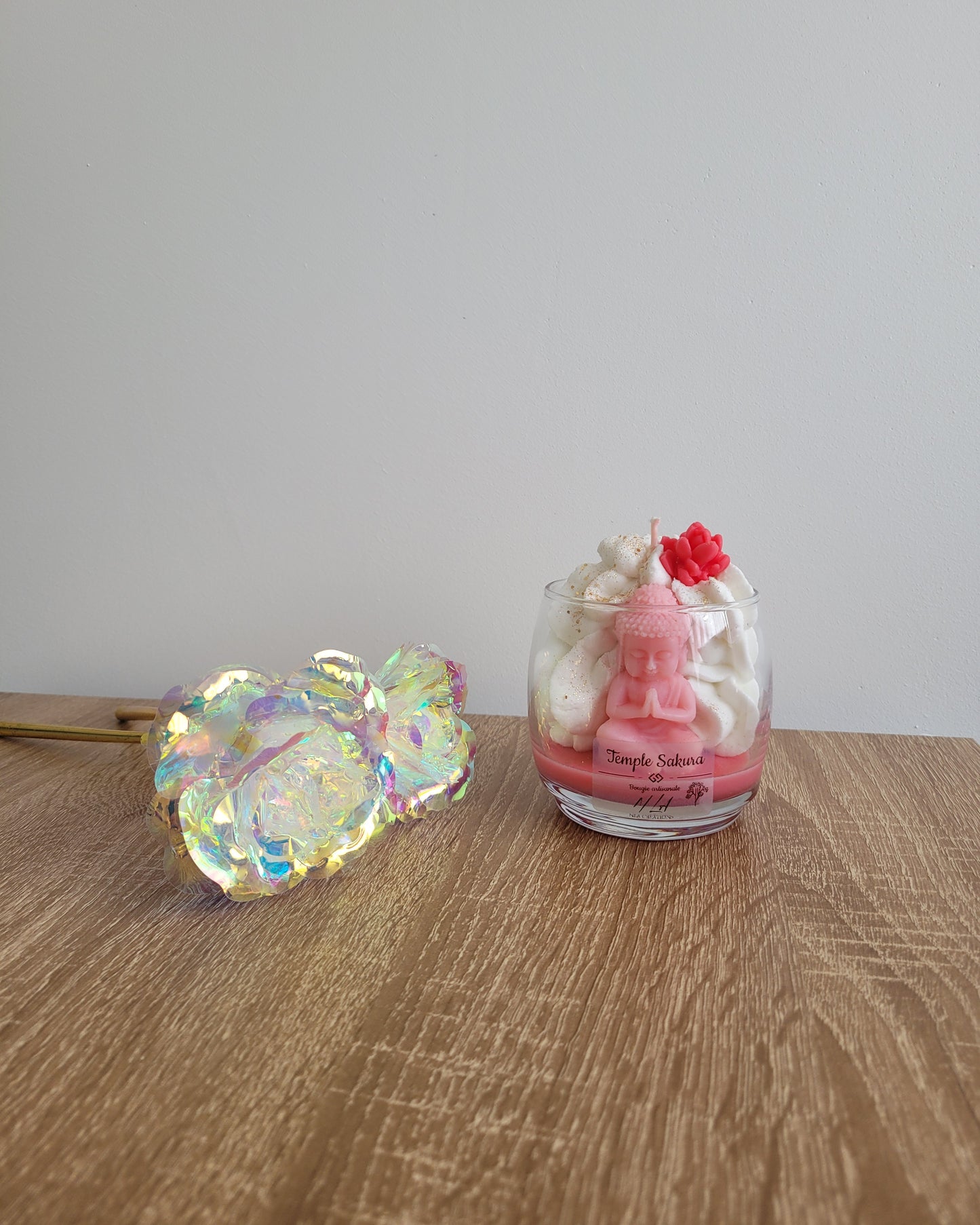 Bougie rose parfumée à la fleur de cerisier, coulée à la main dans un pot en verre avec une figurine de Bouddha et des paillettes dorées.