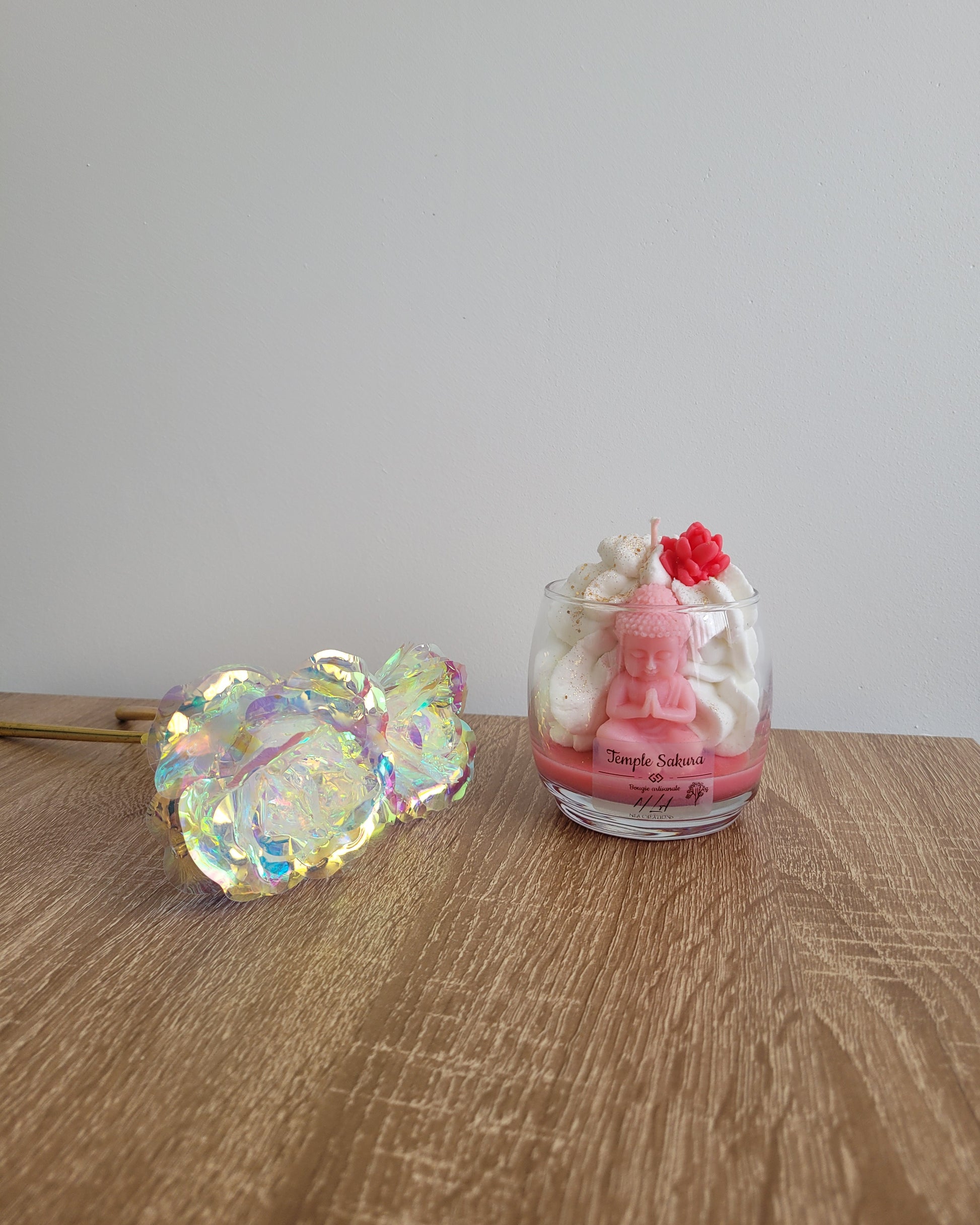 Bougie rose parfumée à la fleur de cerisier, coulée à la main dans un pot en verre avec une figurine de Bouddha et des paillettes dorées.