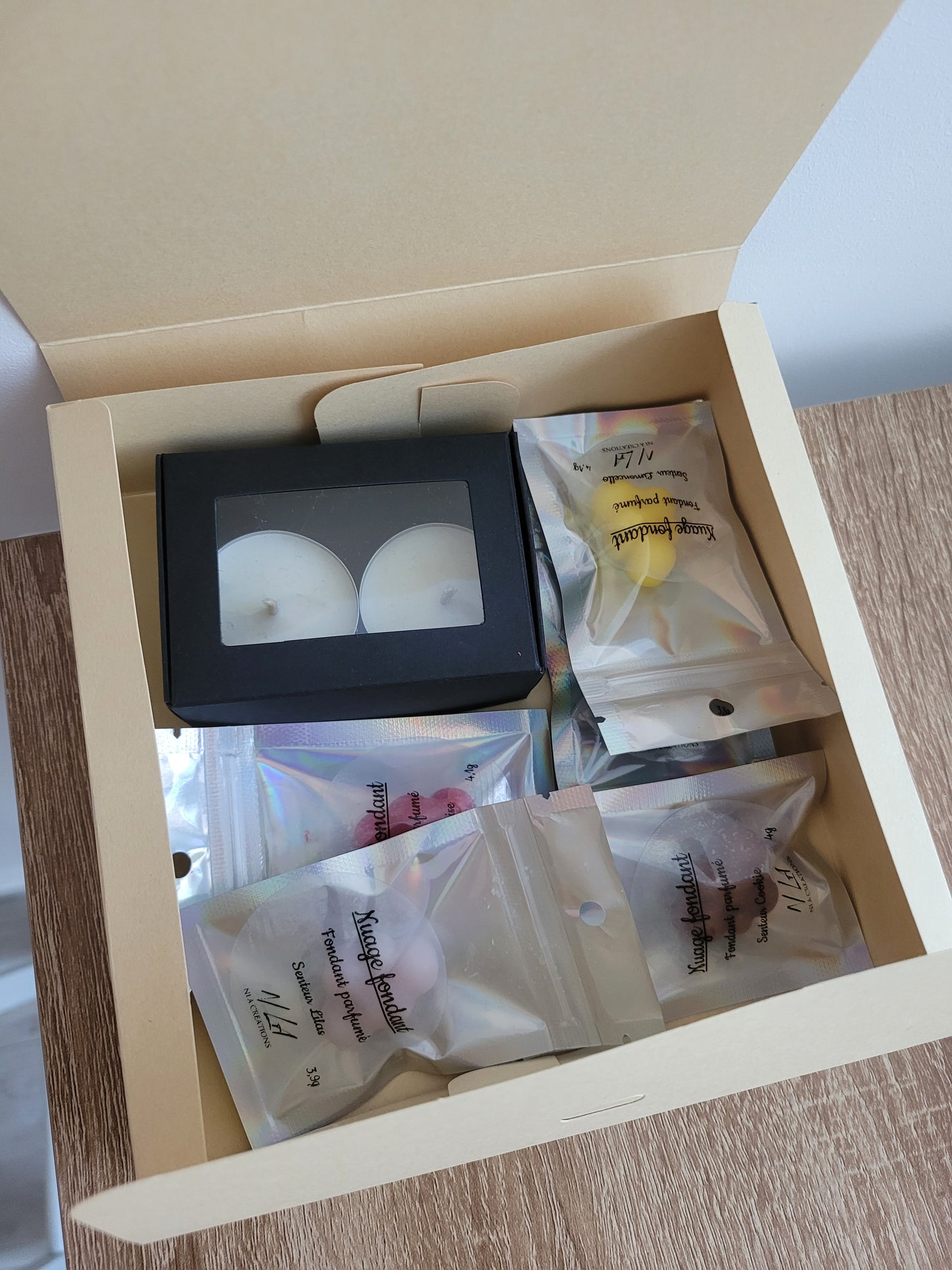 Assortiment de cinq fondants parfumés faits main, aux formes et couleurs variées, posés sur une surface décorative.