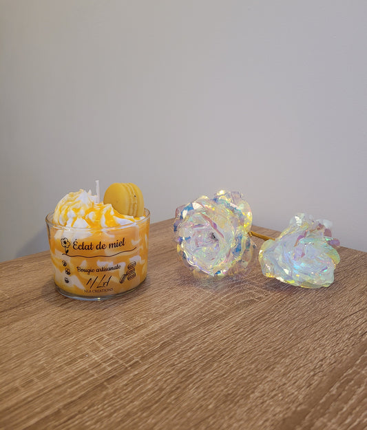 Bougie artisanale couleur miel, présentée dans son contenant en verre, avec un macaron décoratif posé sur la chantilly. Parfum Miel Avoine, ambiance douce et réconfortante.