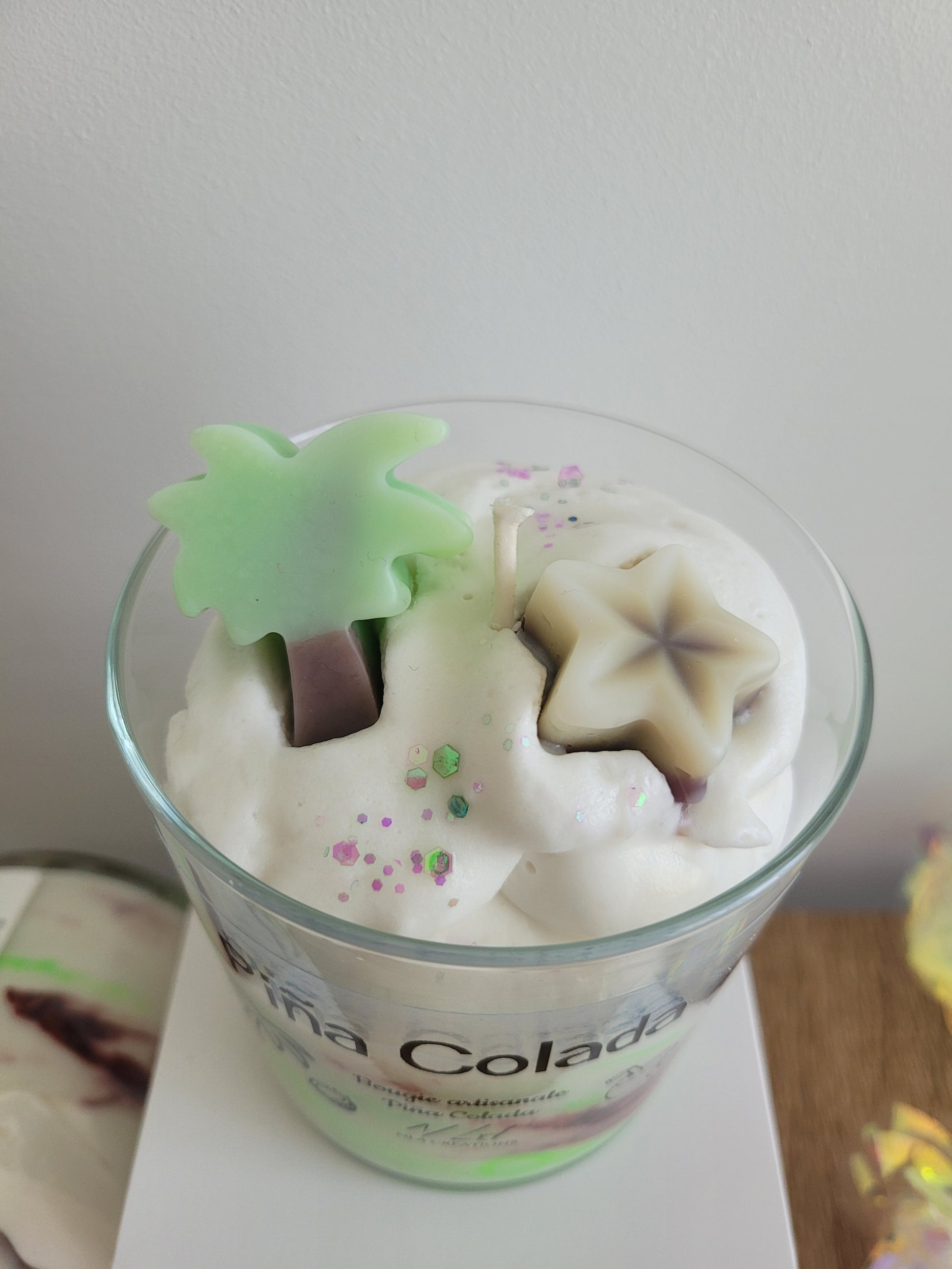 Vue du dessus de la bougie artisanale Pina Colada, décorée de cire fouettée et de formes en cire tropicales comme un palmier